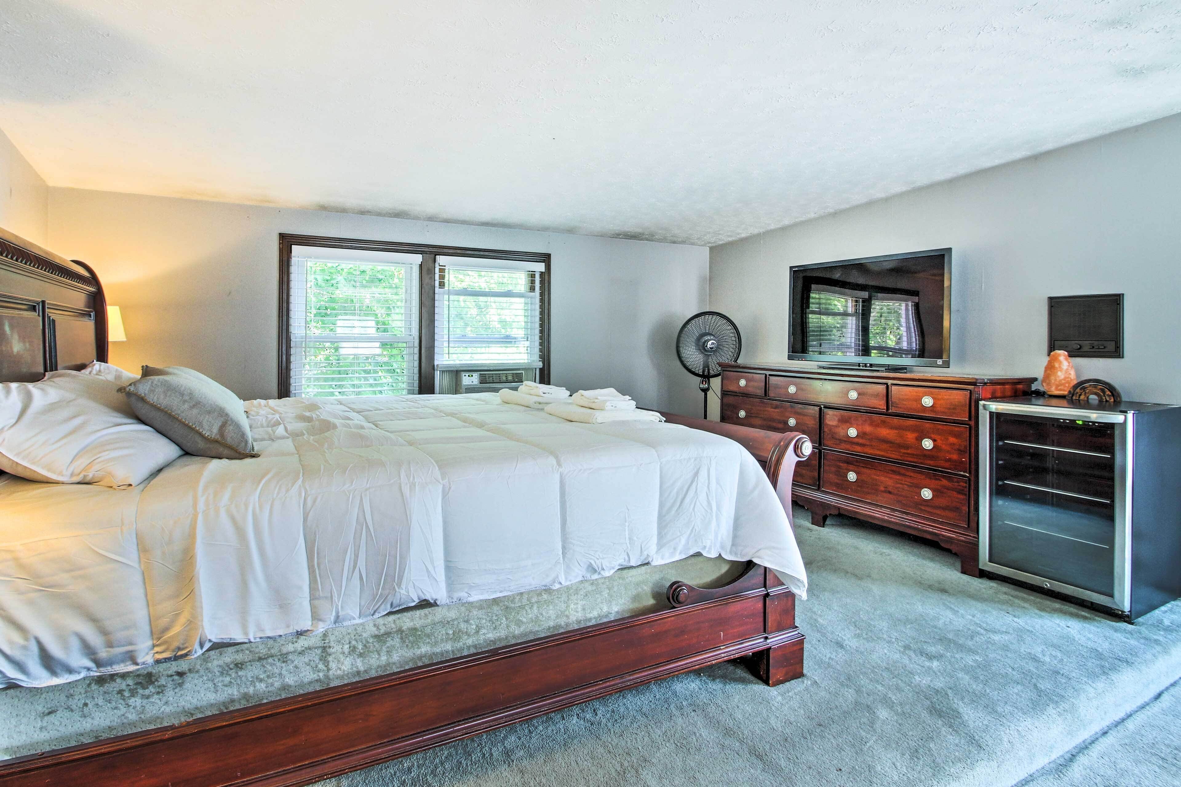 Une chambre à coucher avec un grand lit, une commode, une télévision et un ventilateur.