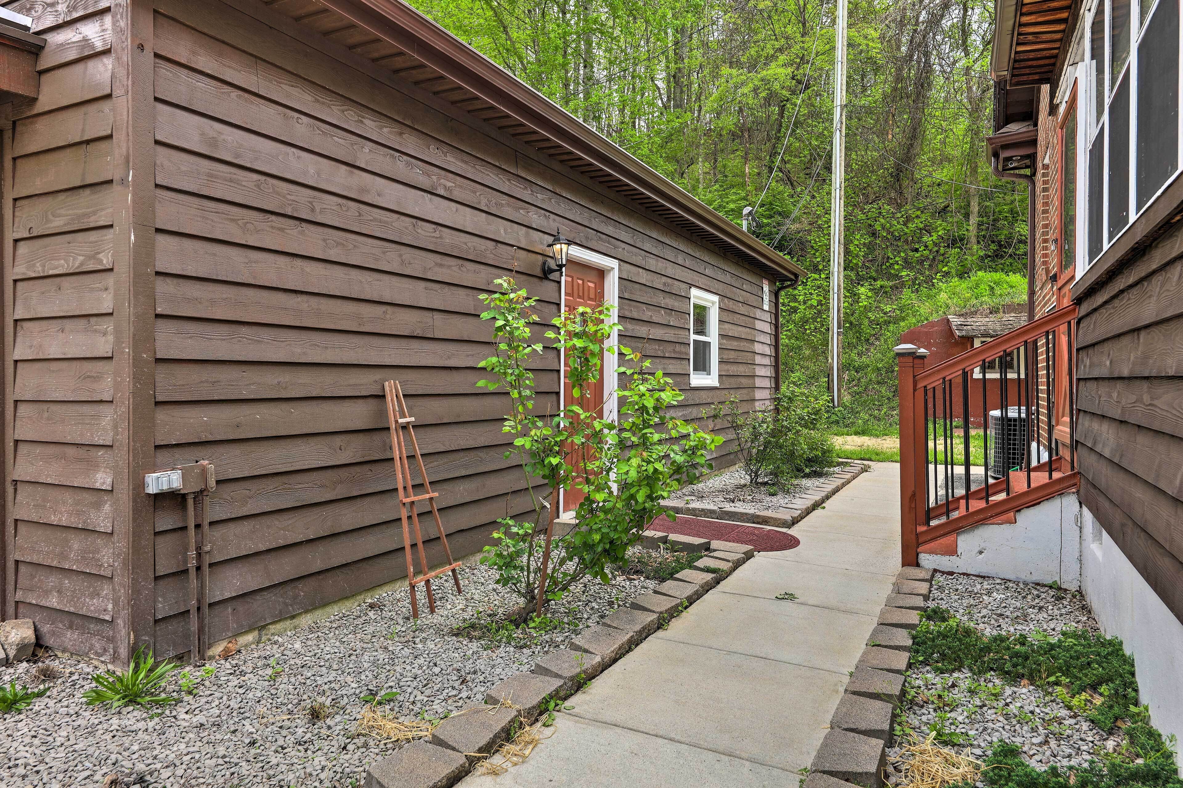 A wooden cabin with a small porch, a ladder, and a pathway leading to the entrance.