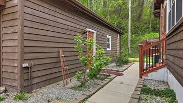 A wooden cabin with a small porch, a ladder, and a pathway leading to the entrance.