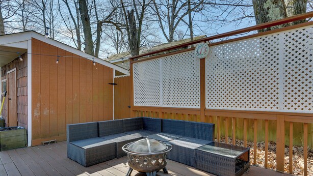 Une terrasse en bois dotée d’un espace salon intégré et d’un foyer extérieur.