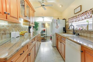 A kitchen with wooden cabinets, a granite countertop, a ceiling fan, and a refrigerator.