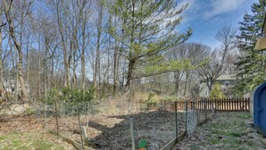 Un jardin avec un parterre surélevé, une clôture en bois et des arbres.