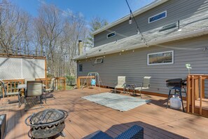 A deck with outdoor furniture, a grill, and a pergola.