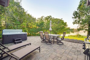 An outdoor patio with a hot tub, lounge chairs, and a table with chairs. - Patio, Views & Hot Tub: Quiet Lakeside Cabin (Grantsburg)