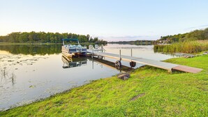 Un bateau était amarré à un quai, avec une zone herbeuse et des arbres en arrière-plan.