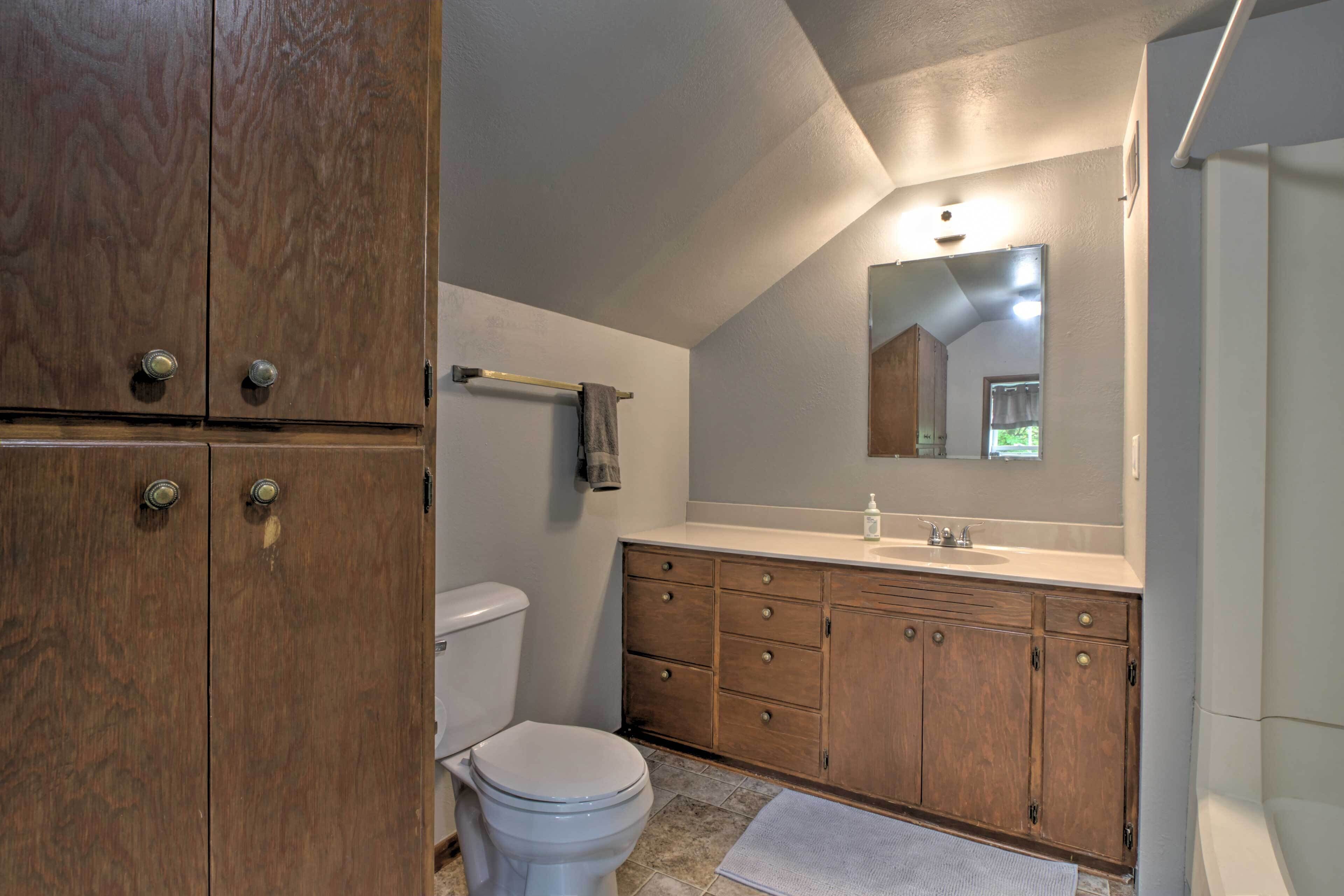 A bathroom with a wooden vanity, a white toilet, and a mirror above the sink.