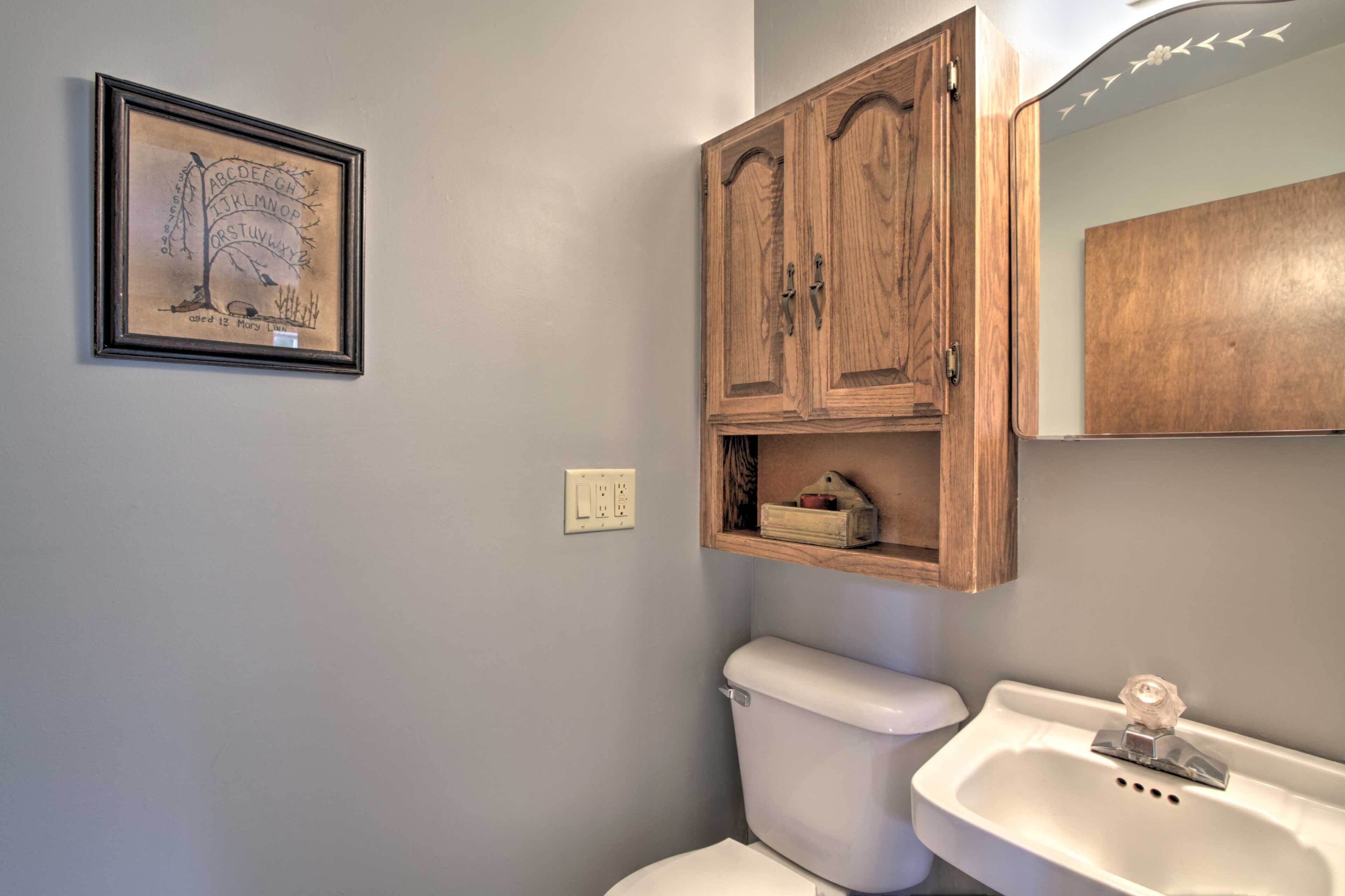 A bathroom with a toilet, a sink, and wooden cabinets above the toilet.