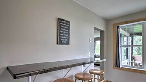 Eine Küche mit Marmorarbeitsplatte, Holzstühlen und einem motivierenden Zitat an der Wand.