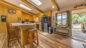 A spacious kitchen with wooden cabinets, a central island, and a large window. - Hot Tub, Deck & Fireplace at Rustic Alto Cabin! (Alto)