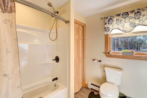 A bathroom with a bathtub, toilet, and a window with a view of trees. - Catskills Getaway w/ Hot Tub on 45 Acres! (Hannacroix)