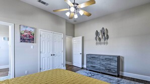 A bedroom with a bed, a ceiling fan, a dresser, and a door. - 8 Mi to White Rock Lake: Spacious Krum Home (Krum)
