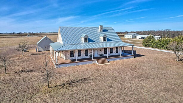 A two-story house with a metal roof, a covered porch, and a fenced yard. - 8 Mi to White Rock Lake: Spacious Krum Home (Krum)