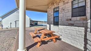A covered patio with a wooden picnic table and stone walls. - 8 Mi to White Rock Lake: Spacious Krum Home (Krum)