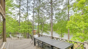 A wooden deck with a table and chairs, overlooking a lake surrounded by trees. - Riverfront Shelby Home w/ Private Boat Dock! (Shelby)