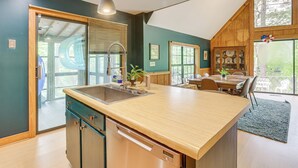 A kitchen with a large island, wooden cabinets, and a dining area with a table and chairs. - Riverfront Shelby Home w/ Private Boat Dock! (Shelby)