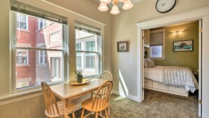 A room with a dining table and chairs, a bed with a headboard, a clock on the wall, and a window with blinds. - Salt Lake City Condo < 28 Mi to Ski Resort! (Salt Lake City)