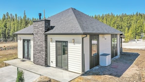 A modern house with a stone chimney, a covered porch, and a view of a forest. - Romantic Mountain Retreat w/ Scenic Views! (Idaho Springs)