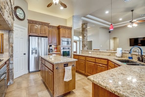A kitchen with granite countertops, wooden cabinets, a built-in oven, and a stone accent wall. - Countryside Retreat! Spacious Home in La Vernia (Adkins)