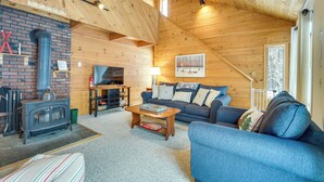 Ein gemütliches Blockhaus-Interieur mit Kamin, Sofa und Fernseher.