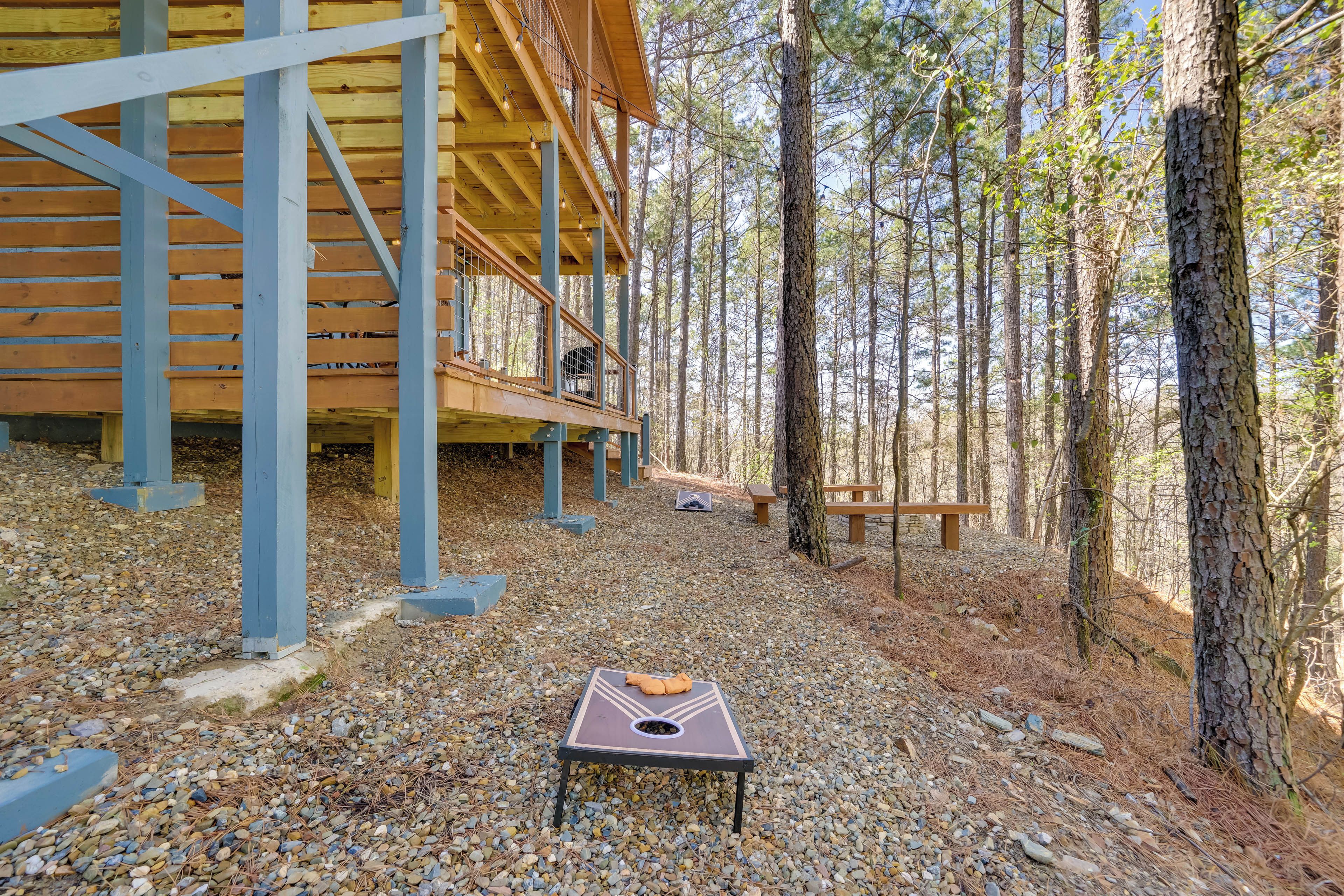 A wooden cabin with a gravel ground, surrounded by trees.