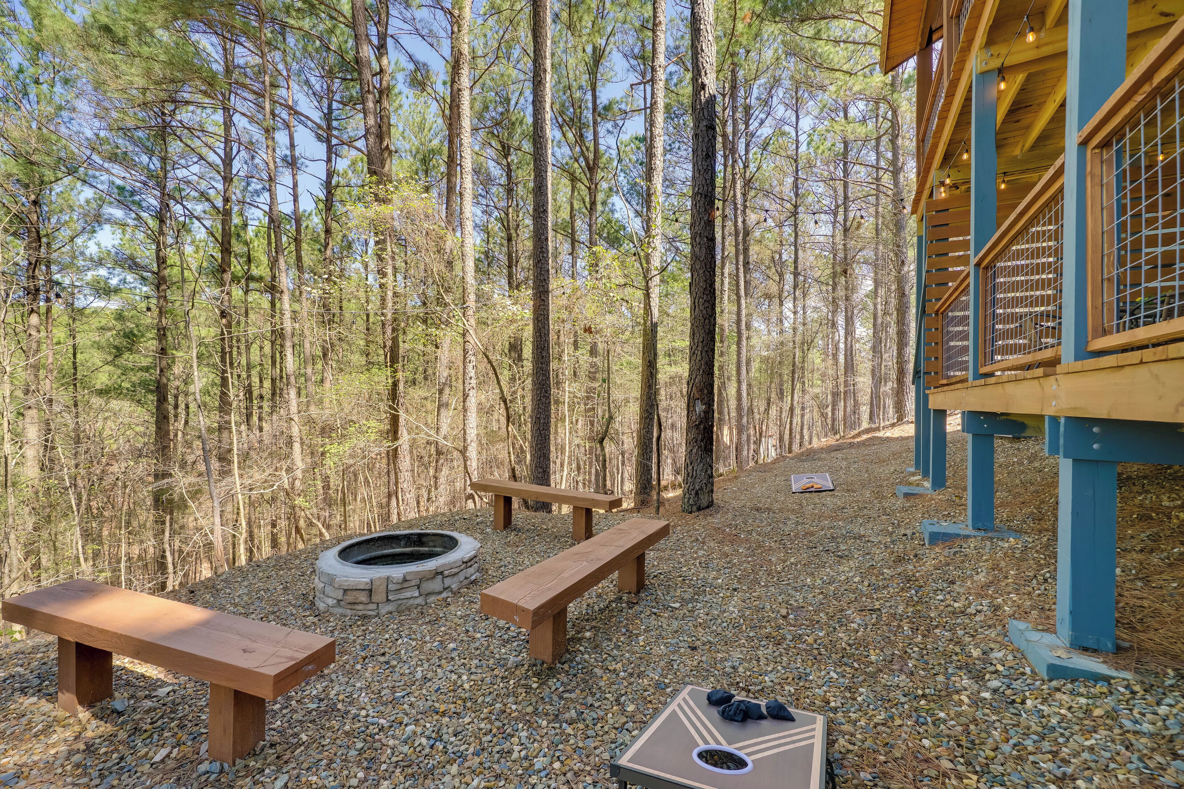 A forested area with wooden benches and a fire pit.