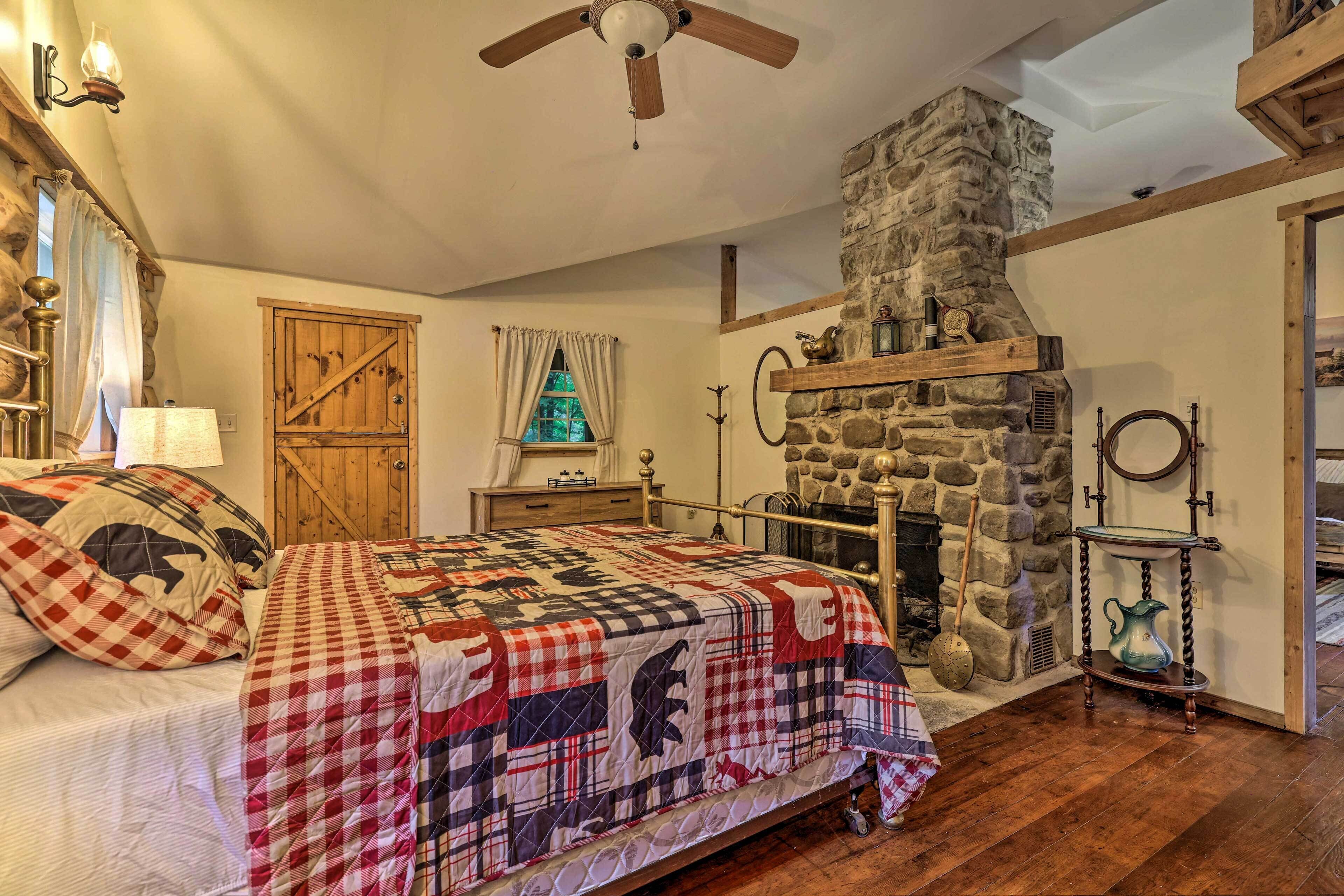 A cozy bedroom with a stone fireplace, a bed with a quilt, and a wooden door.