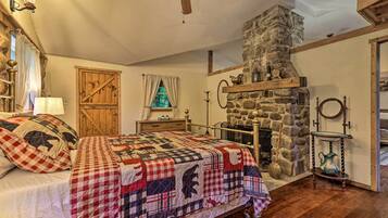 A cozy bedroom with a stone fireplace, a bed with a quilt, and a wooden door.