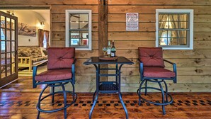 A wooden cabin interior with two bar stools, a table with bottles, and a welcome sign. - Trails & Creek On-site: Tranquil Greentown Cabin (Greentown)
