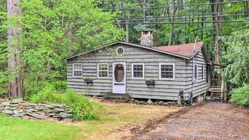 A rustic cabin with a stone foundation, wooden siding, and a chimney.
