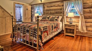 A rustic bedroom with a metal bed frame, wooden walls, and a wooden floor. - Trails & Creek On-site: Tranquil Greentown Cabin (Greentown)