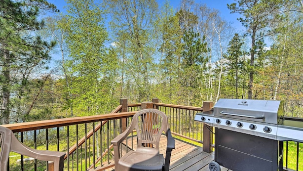 A deck with a barbecue grill, a chair, and a table. - Waterfront Escape w/ Fire Pit in Crosslake! (Pequot Lakes)