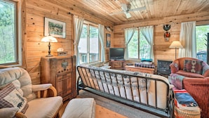 A cozy cabin interior with wooden walls, a bed, a television, and a fireplace. - Waterfront Escape w/ Fire Pit in Crosslake! (Pequot Lakes)