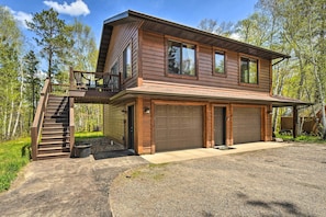 A two-story house with a front deck, a staircase, and a garage.