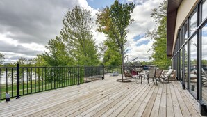 A wooden deck with outdoor furniture, a railing, and a view of trees and a cloudy sky. - Cozy Cassopolis Cabin, Near Parks & Golfing! (Cassopolis)