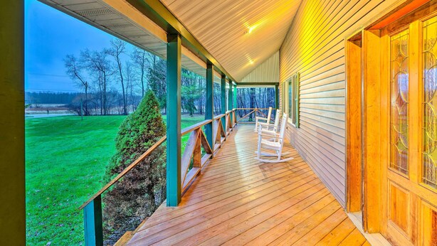 Un portico coperto con ringhiere in legno e vista su un paesaggio verde.