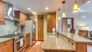 A kitchen with wooden cabinets, a stainless steel range hood, a granite countertop, a built-in oven, a sink, and pendant lighting. - Central Mccall Getaway: Walk to Payette Lake! (McCall)