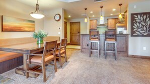A spacious kitchen with wooden cabinets, a dining area with a bench, and pendant lighting. - Central Mccall Getaway: Walk to Payette Lake! (McCall)
