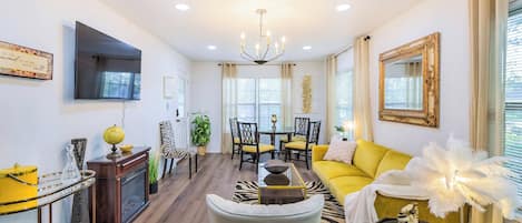 Una sala de estar moderna con un sofá amarillo, un felpudo de cebra y una zona de comedor con una araña.