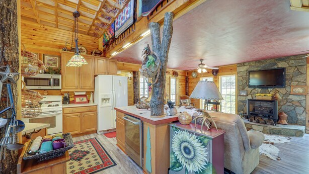 L’intérieur d’un chalet rustique comprend une cuisine, un espace de vie et une cheminée en pierre.
