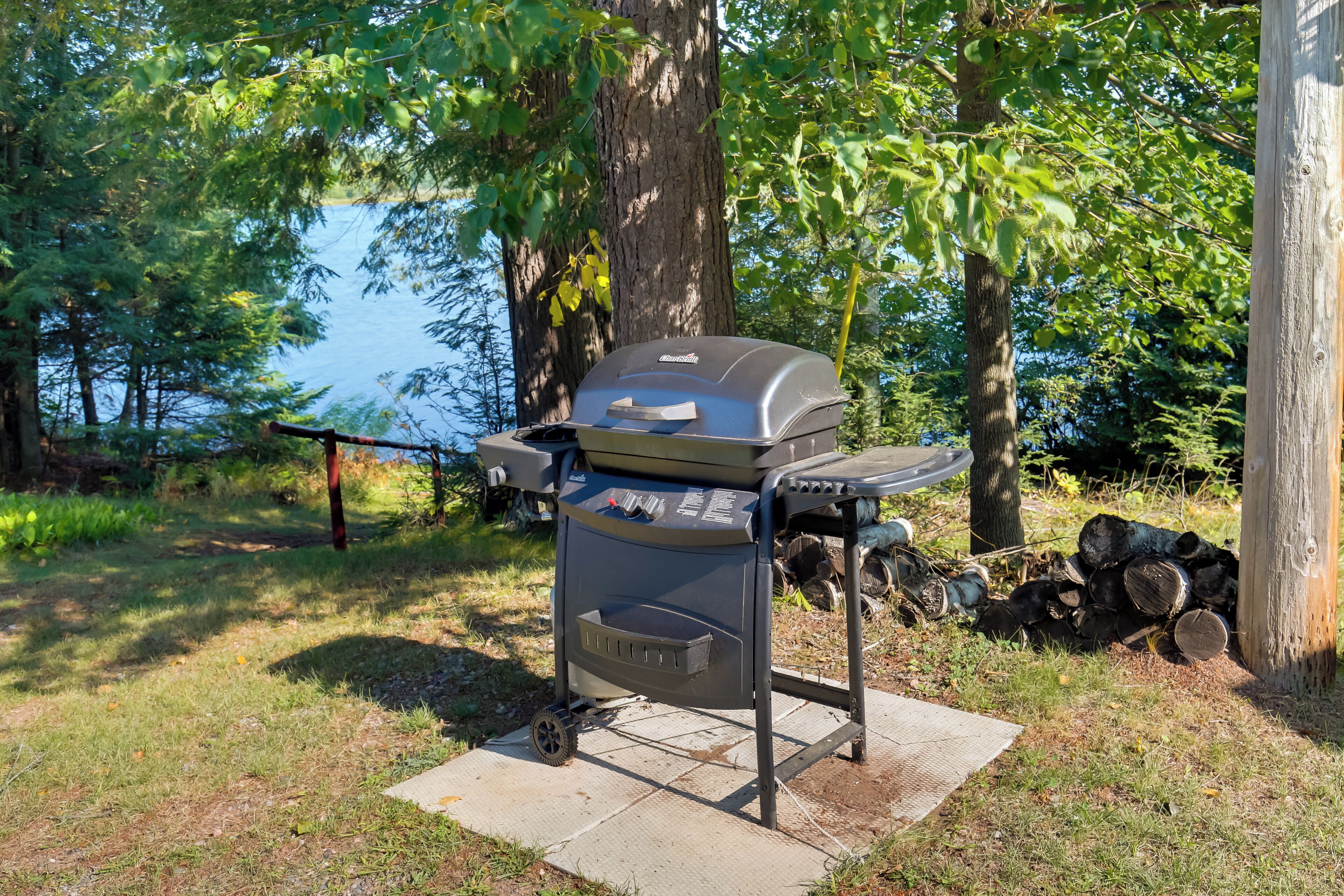 A portable grill set up in a grassy area with a lake in the background.