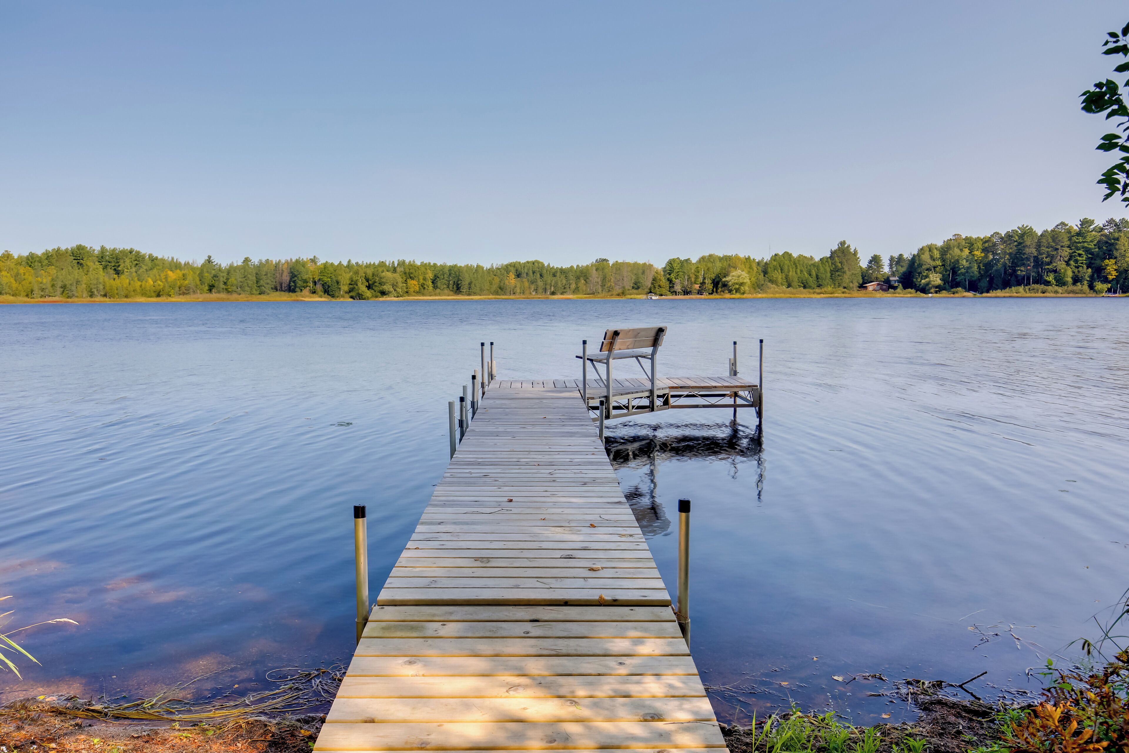A wooden dock extending into calm water with a bench at the end.