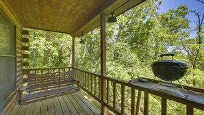 A wooden porch with a bench, a grill, and a view of a forest. - Secluded Studio w/ Deck ~ 8 Miles to Beaver Lake! (Eureka Springs)