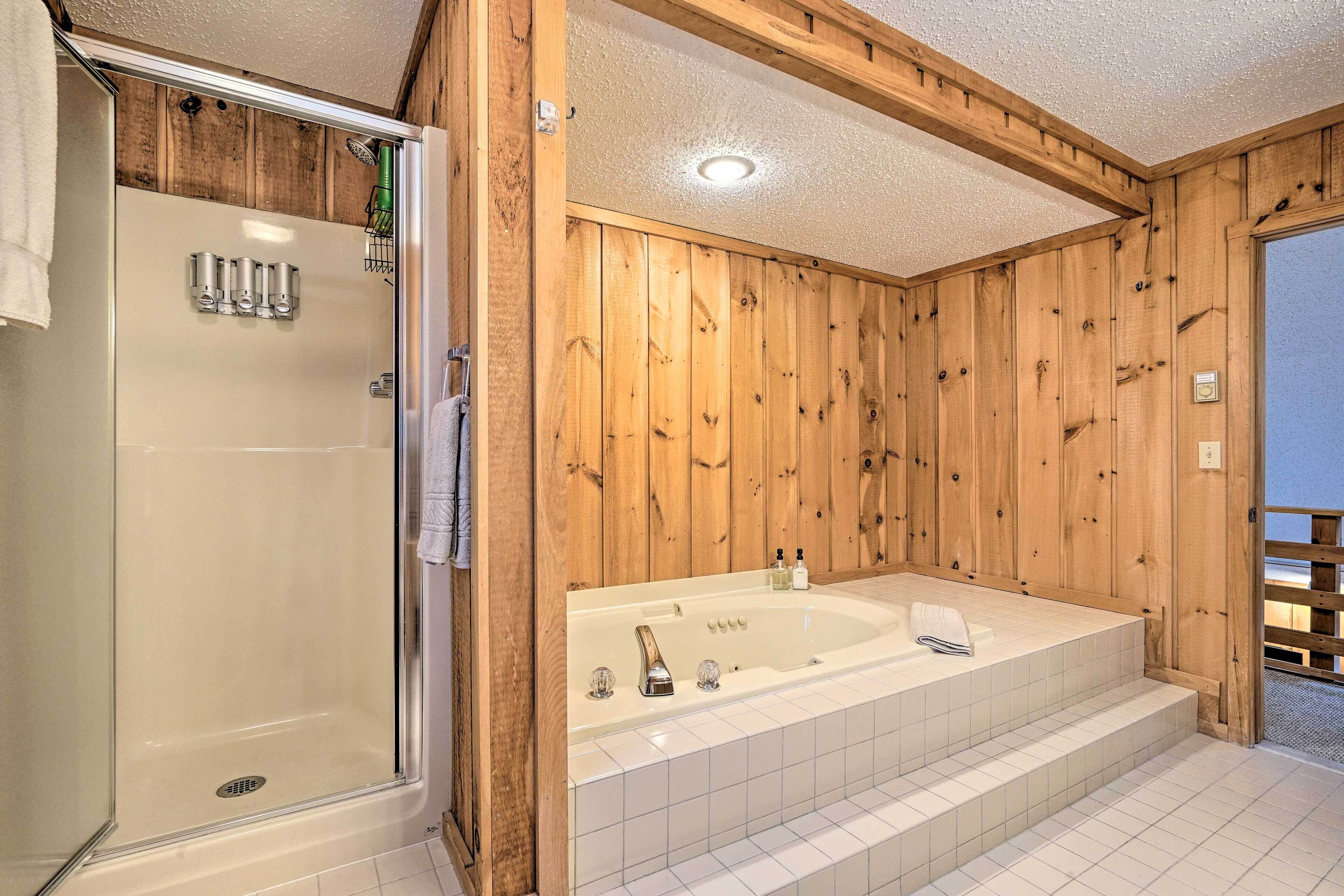 Une salle de bain aux murs lambrissés, dotée d’une douche à parois de verre, d’une baignoire sur pieds et d’un sol carrelé.