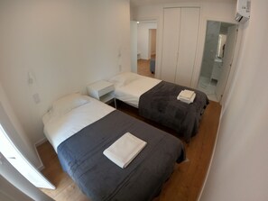 A bedroom with two single beds, a nightstand, and a wardrobe.