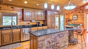 A spacious kitchen with wooden cabinets, a granite countertop, and a stone island.
