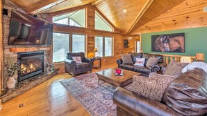 A spacious living room with a fireplace, leather sofas, and a large TV.