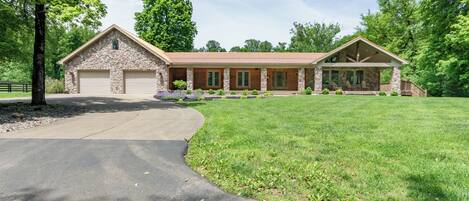 A two-story stone house with a large garage, a covered porch, and a well-maintained lawn.