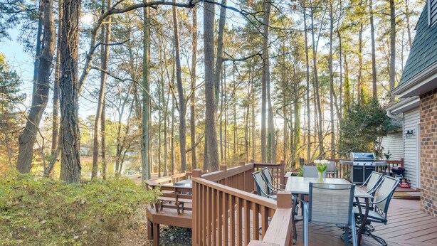 Eine Terrasse mit Gartenmöbeln, einem Grill und Blick auf einen Wald.