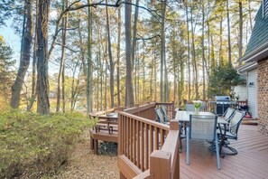 Una terraza con mobiliario exterior, una parrilla y vistas a un bosque.
