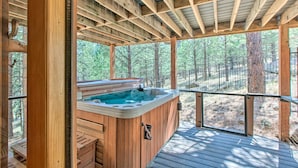 Eine Holzterrasse mit Whirlpool, umgeben von Bäumen.